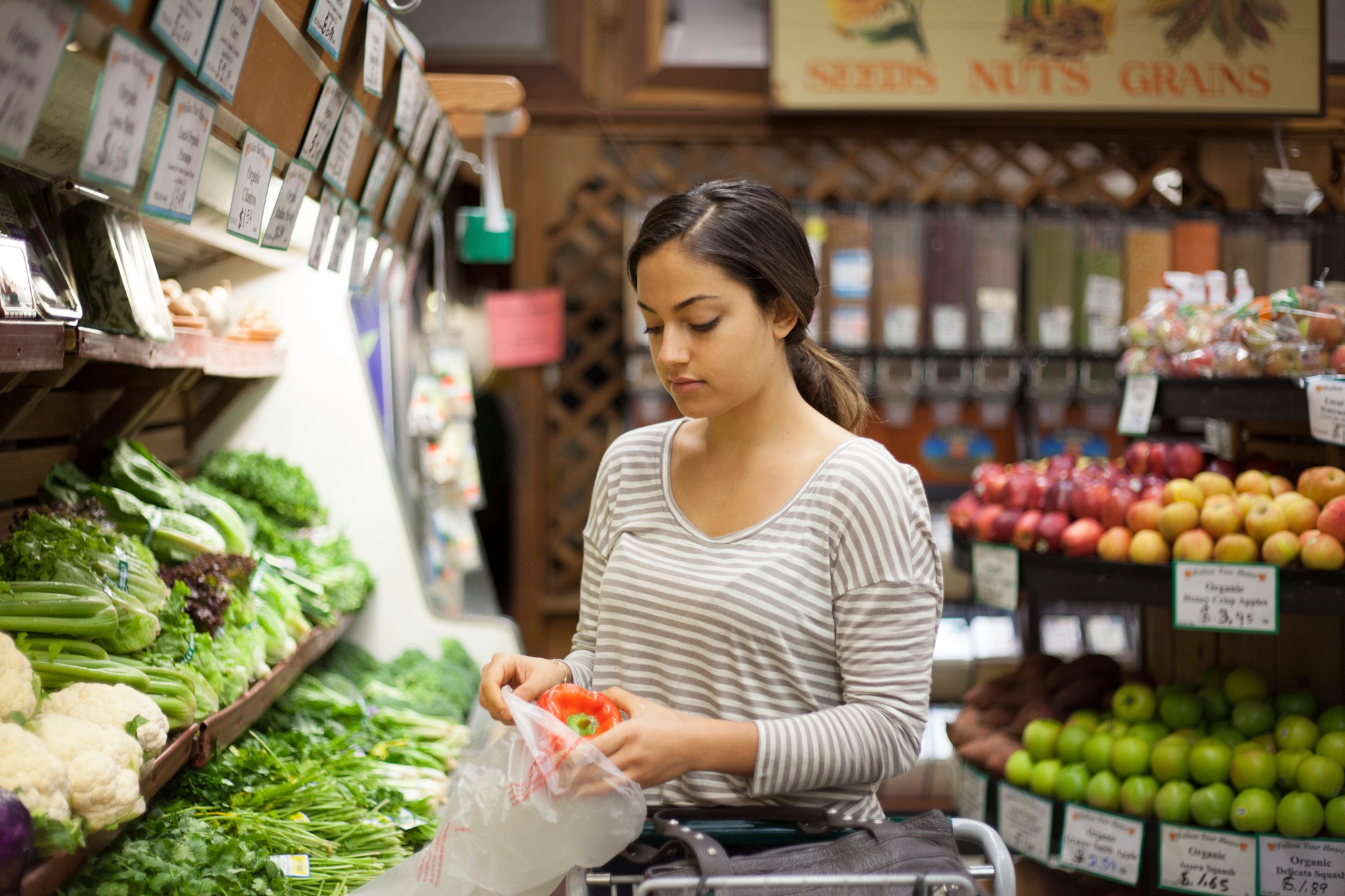 Young woman selecting red pepper at health food store